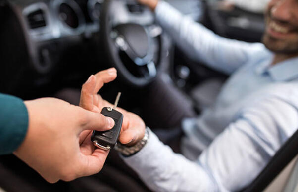 A rental agent handing car keys to a customer, symbolizing the start of a car rental experience.